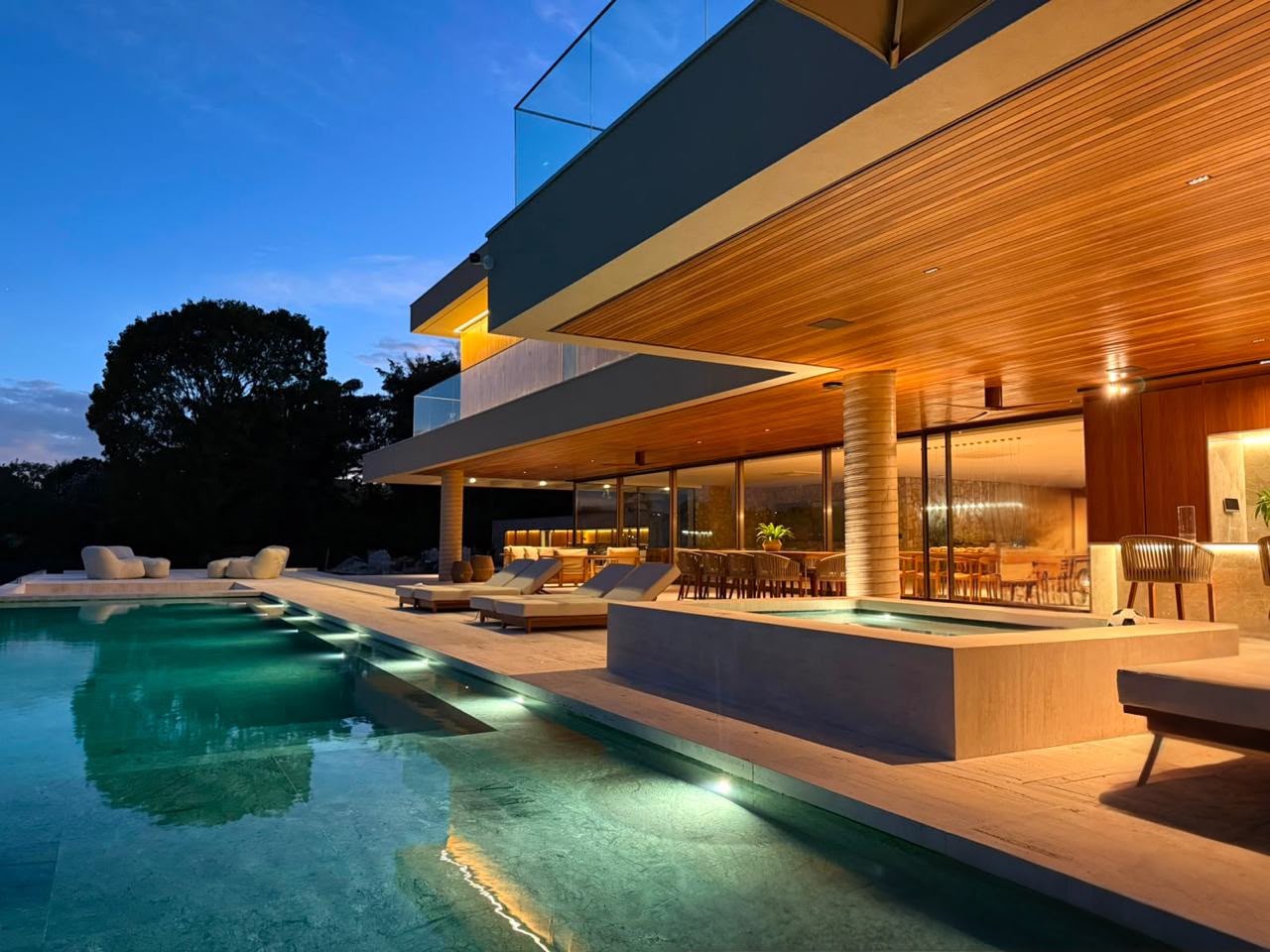 Fachada iluminada ao entardecer com piscina e SPA