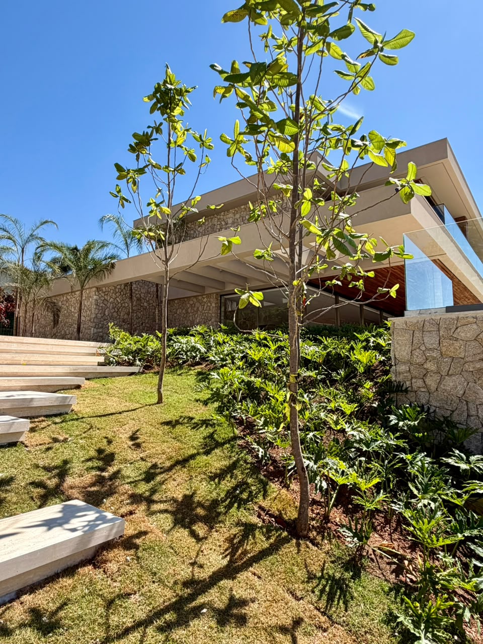 Fachada vista do jardim com escada de pedra e paisagismo